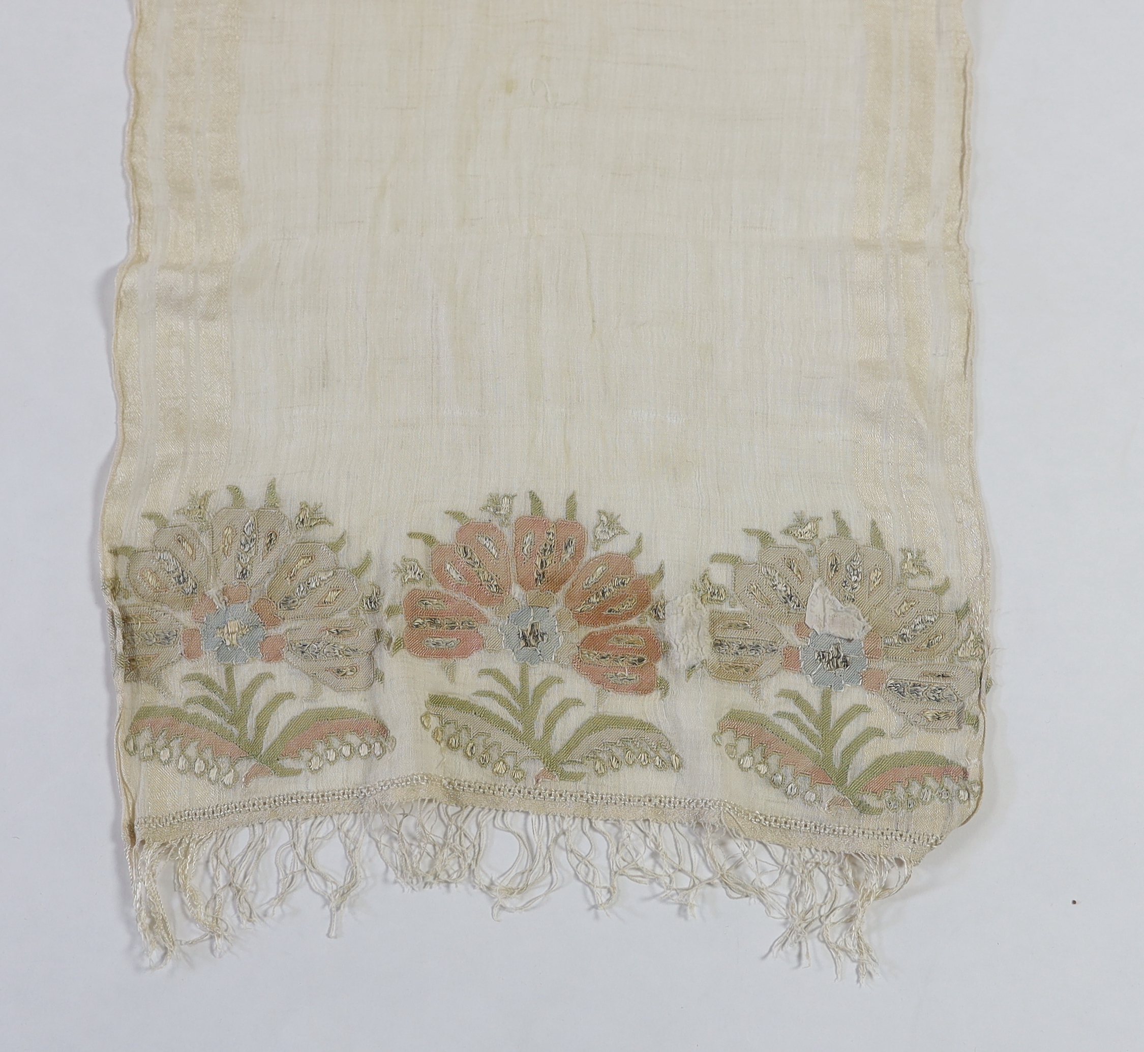 A 19th century Turkish towel, embroidered with flower motifs, in pastel shades, with fine silk fringing embroidered onto a fine hand spun linen, woven with stripes to each side, 48cm wide, 120cm long